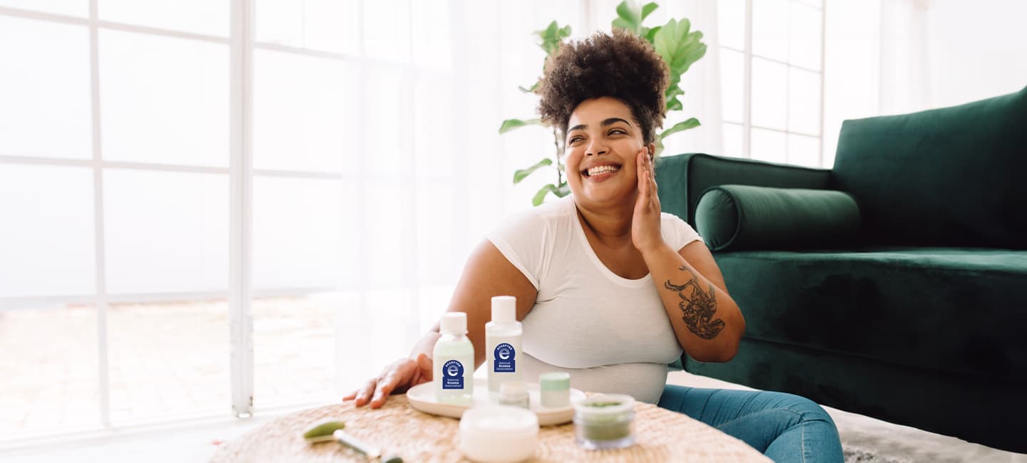 Black female smiling and applying NEA Seal of Acceptance products to face
